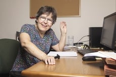 A woman sits at her desk smiling