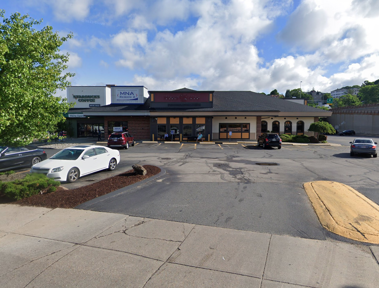 A one-story building containing three storefronts with a parking lot in front. 
