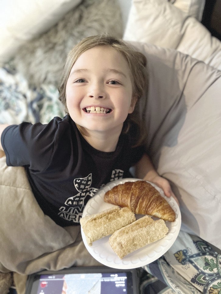 A photo of Noah Kane holding a plate of bread and croissants