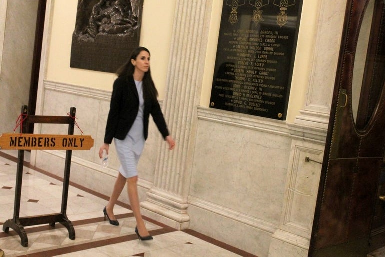 A woman walks through a marble hallway