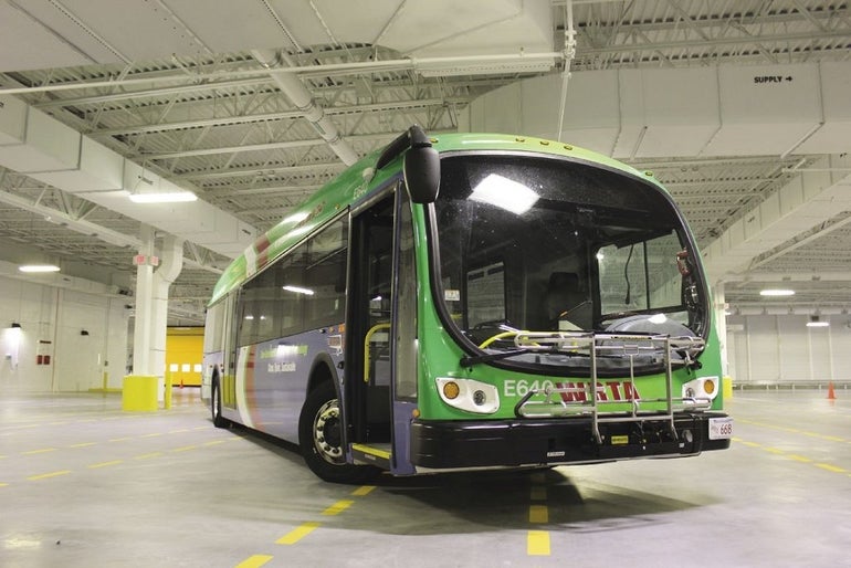 A green WRTA bus drives through a parking garage. 