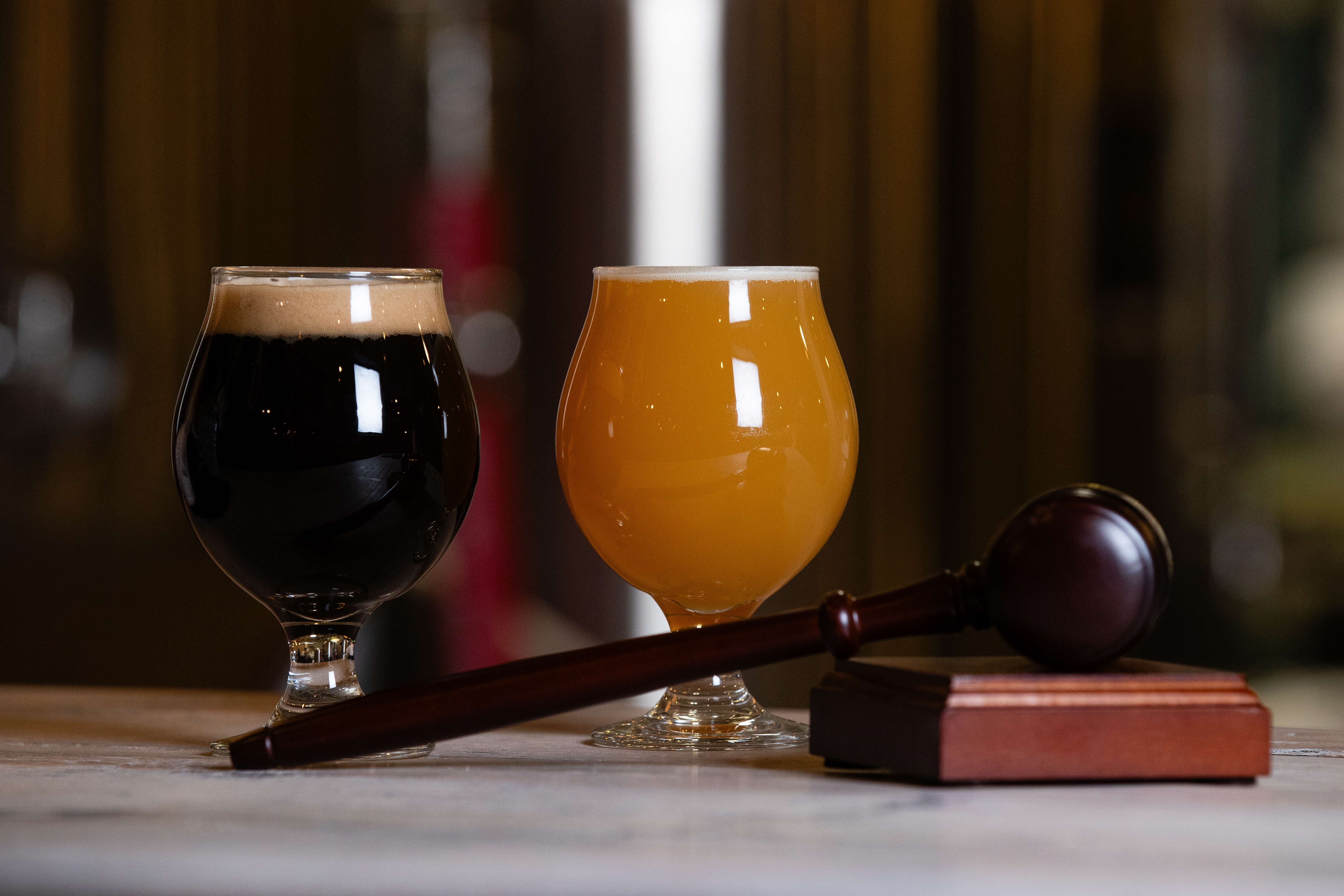 two glasses of beer sit behind a gavel