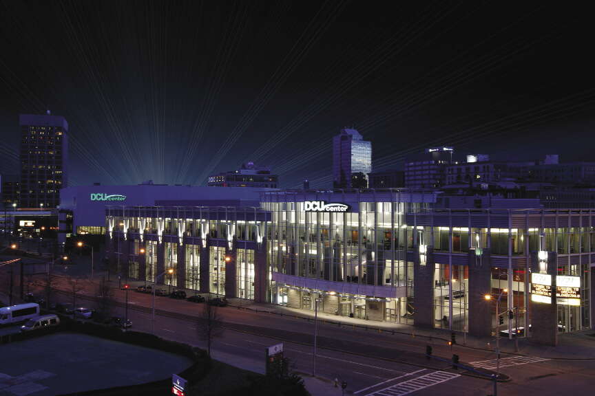 A large building with large glass windows behind a city street at night