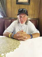 A man sits in a diner booth looking at the camera