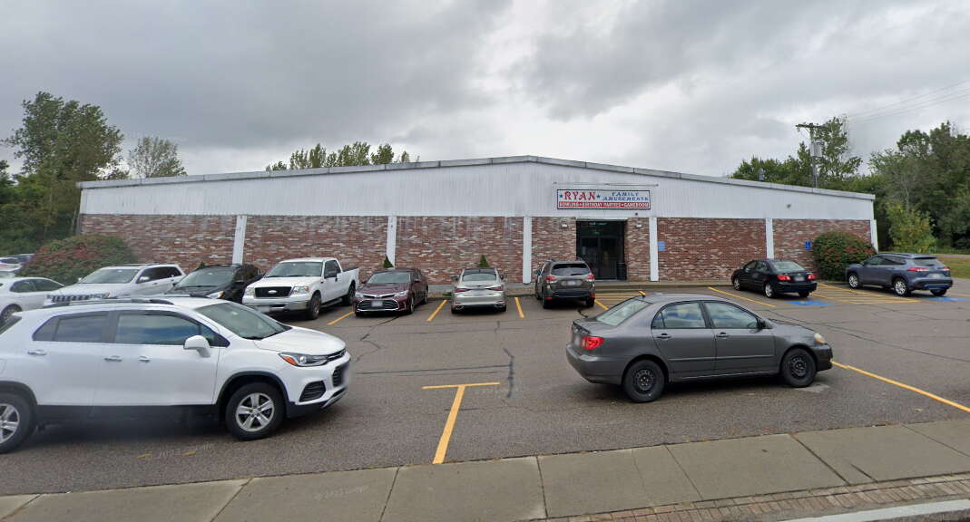 The outside of a bowling alley with cars parked in front