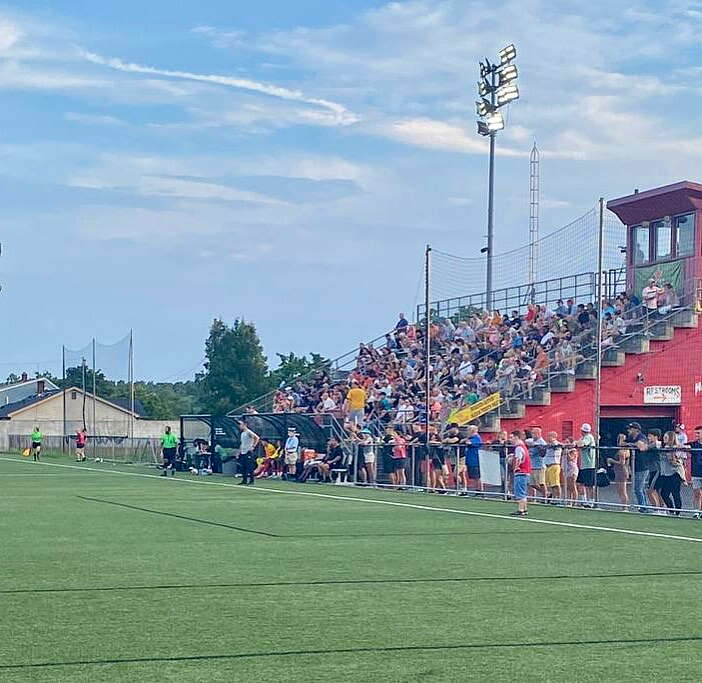 A crowd of people in stands watch a soccer game