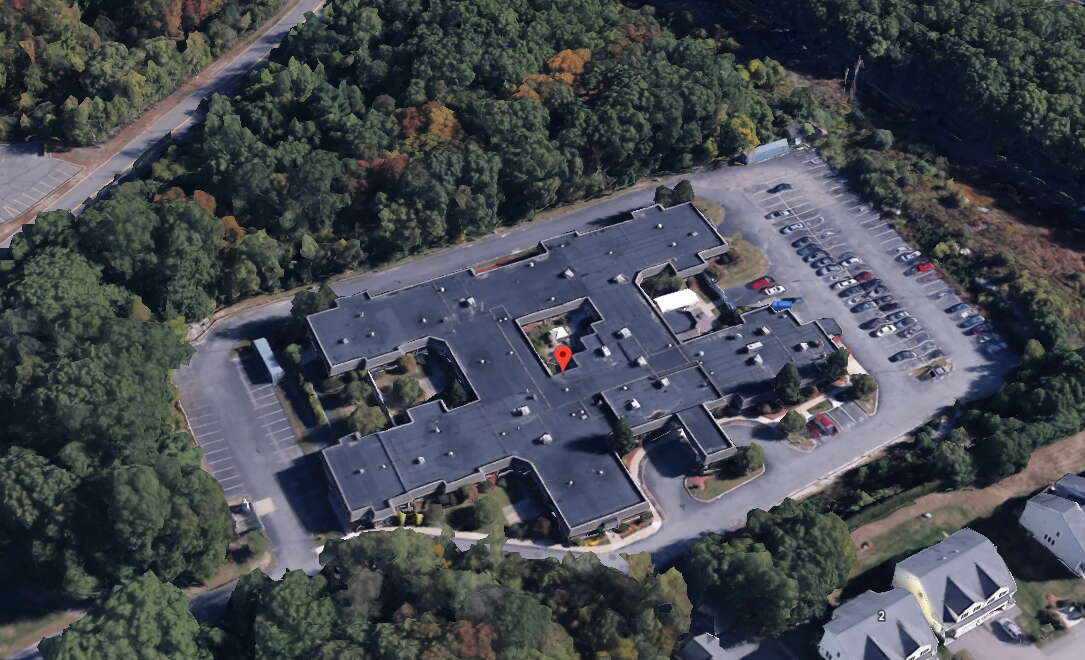Aerial view of a one-story nursing facility surrounded by woodlands