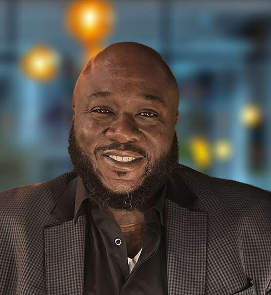 A man with a beard and a brown suit looks at the camera