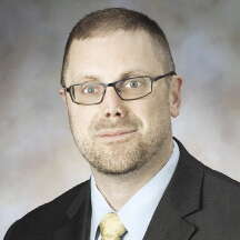 Portrait photo of a man in a suit with glasses