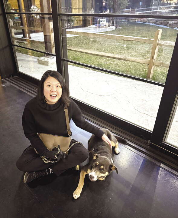 A woman sits on the ground next to her dog