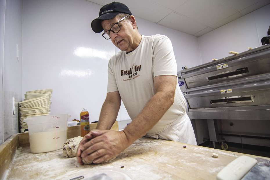 Chuck Brown kneads some dough on a flour covered board.