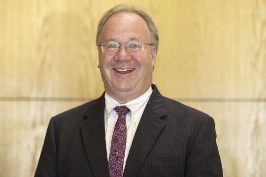 A man with glasses wears a suit.