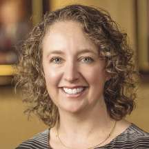 A woman with blonde curly hair smiles for the camera.