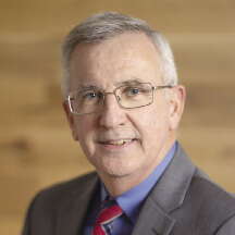 Portrait photo of a man in a suit with glasses