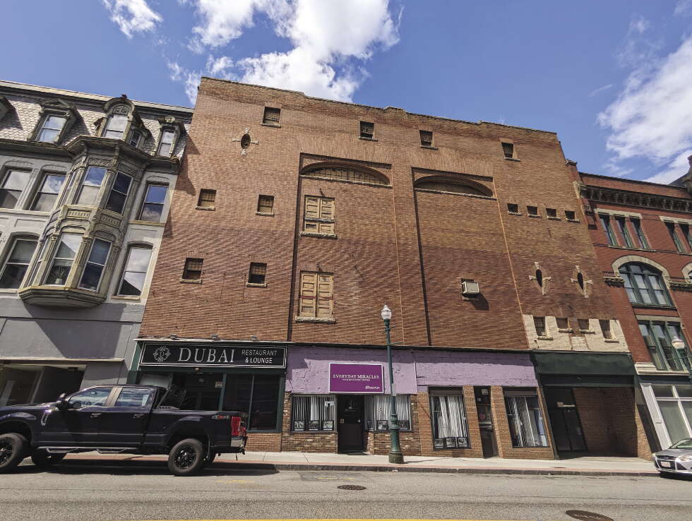 A large, blank brick facade over some retail storefronts