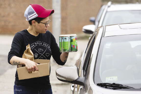 Person hands a four pack of beer to someone through a car window