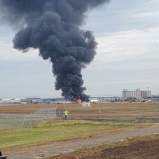 A pillar of smoke rises out of the flaming wreckage of an airplane at a Connecticut airport.