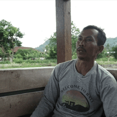An Indonesian man is talking with a green landscape in the background
