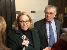 A woman and a man stand in front of microphones