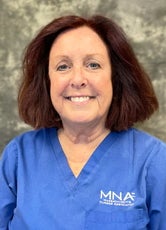 A woman with brown hair wearing a blue shirt smiles at the camera.