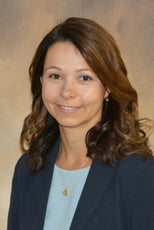 A headshot photo of a woman with brown hair wearing a blue shirt.