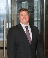 A man in a black suit and red print tie