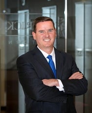 A man in a dark blue suit and light blue tie