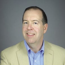 A man in a grey suit poses for a portrait photo