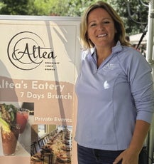 A woman stands in front of a banner for a resturaunt 