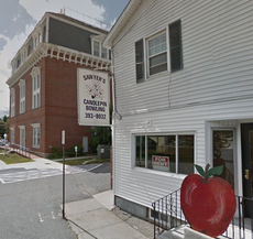 The outside of a bowling center with a sign on the building adversting the bowling center