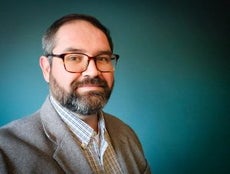 A man with a beard wearing glasses and a gray suit