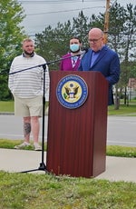 A man in a blue suit speaks at a podium