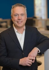 Man in suit leans on a filing cabinet