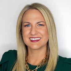 Woman in green shirt smiles while wearing a gold chain necklace