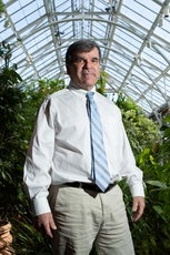 Tim Garvin poses for a portrait photograph in a greenhouse