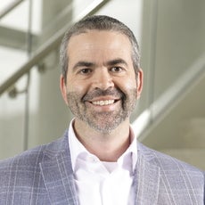 A man in a white shirt and light grey pinstripe suit jacket 