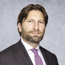 A man with a a beard wears a purple tie.