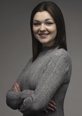 A woman with dark brown hair and a grey mock turtleneck shirt.