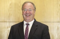 A man with glasses wears a suit.