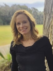 Christine Nolan, smiling with a field and trees in the background