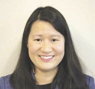 A woman with long black hair wears a blue blazer.