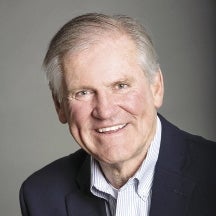 A headshot photo of a man with gray hair wearing a suit