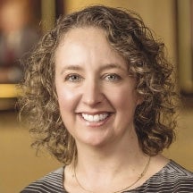 A woman with blonde curly hair smiles for the camera.