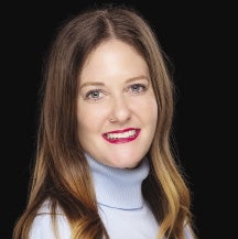 A woman with long brown hair is wearing a blue turtleneck.