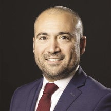 A man with a blue suit and red tie looks at the camera.