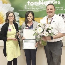 Esparza holding her award between a man and a woman, one holding flowers