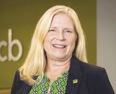 A woman with blonde hair, a green shirt, and a blue jacket
