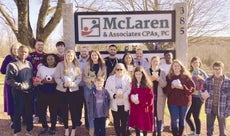 A group of McLaren employees stand in front of a sign.