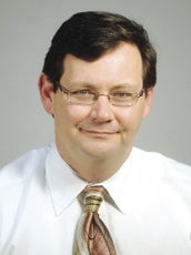 A man with glasses in a white shirt and tie