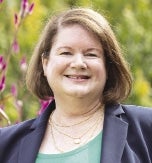 A woman smiling with trees in the background